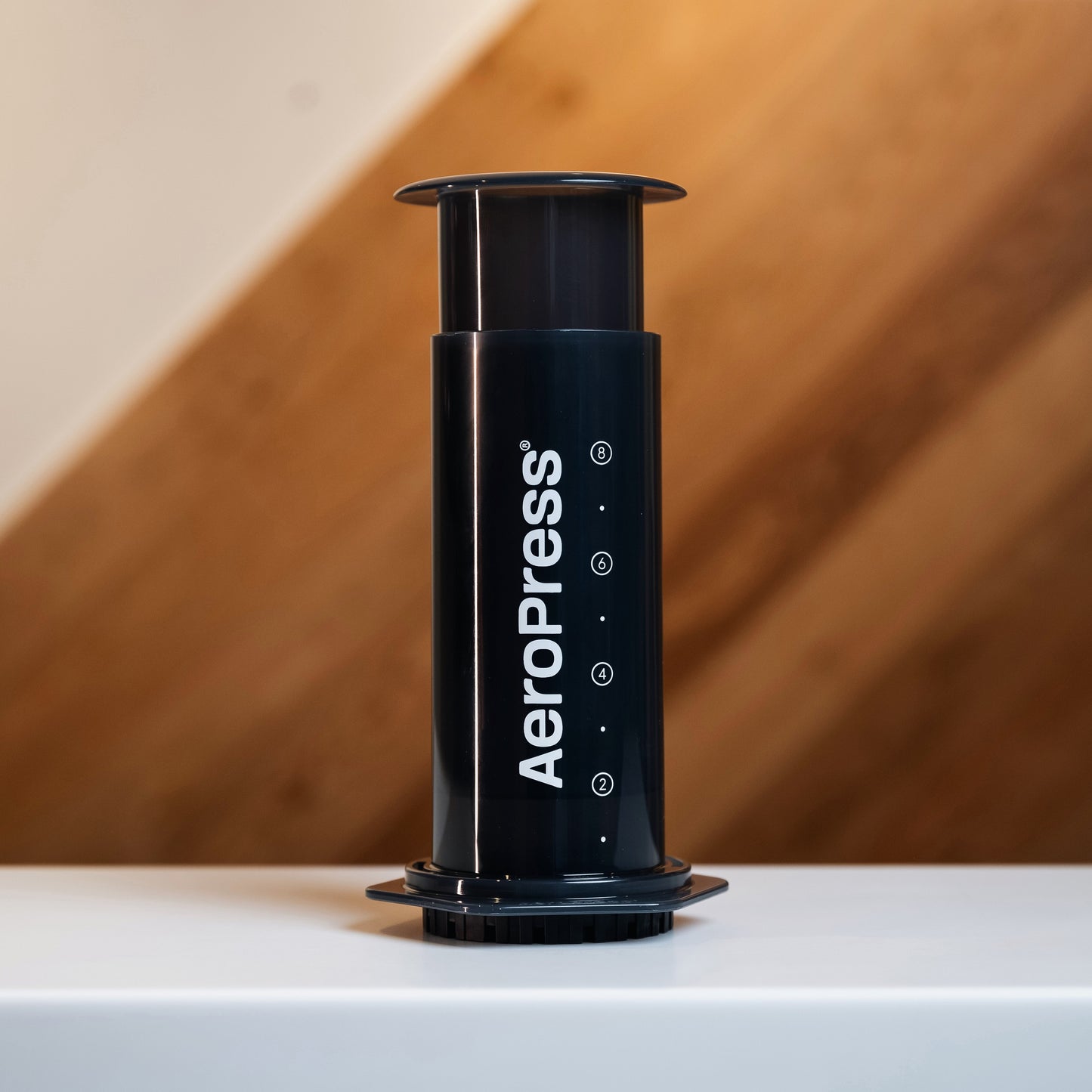 Black plastic aeropress coffee brewer with white branded writing on it 