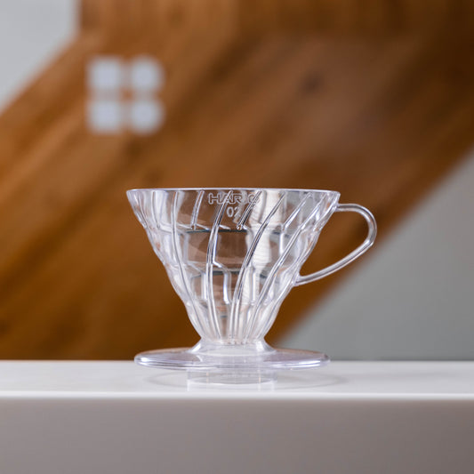 Hario V60 Plastic Dripper - set on a white surface with a blurred wooden background 